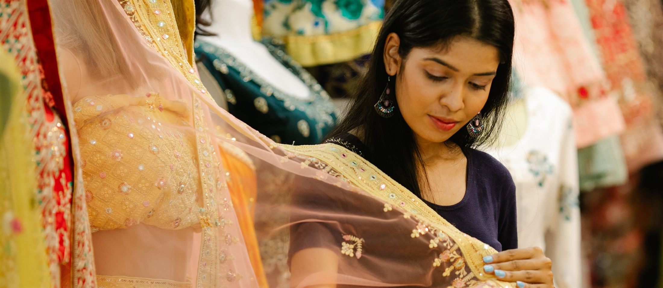 A young woman examining an embroidered dupatta in an Indian clothing store